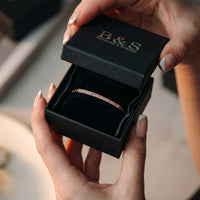Thumbnail for Hands opening the black Brother & Sisters gift box holding the rose gold Crystal Bar Bracelet