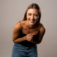 Thumbnail for Smiling woman in casual attire expressing joy and laughter against a neutral background.