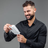 Thumbnail for Man in a black shirt smiling while holding a gift box, showcasing the Minimalist Photo Bracelet by Brother & Sisters.