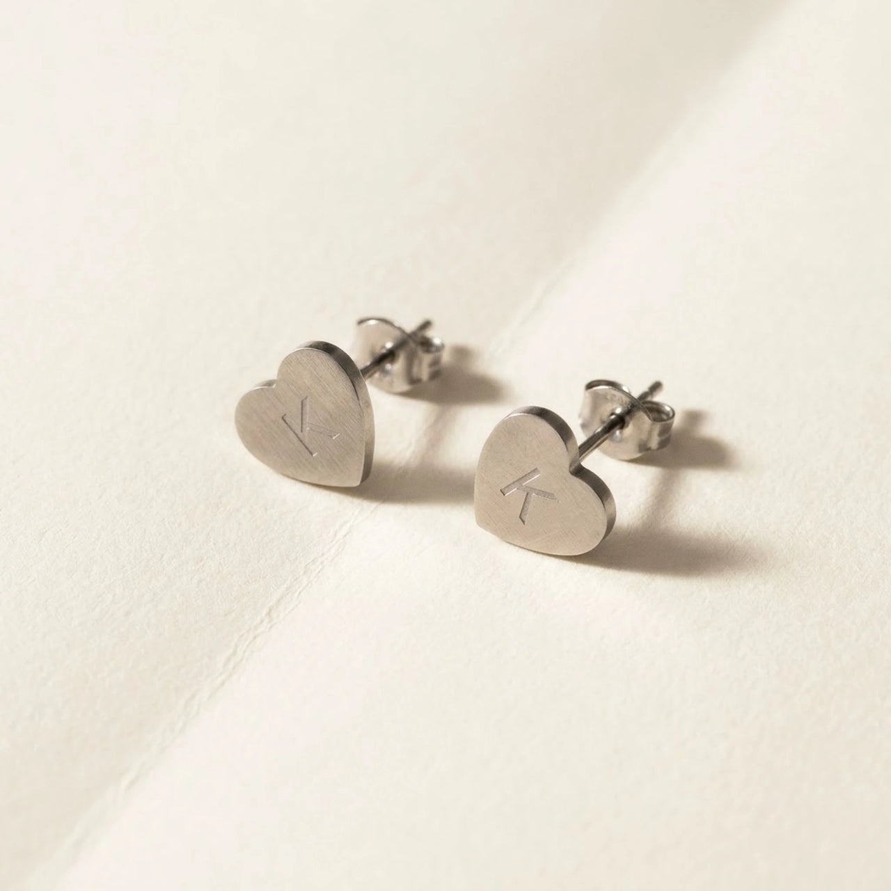 Heart Initial Stud Earrings in Silver, studio packshot of the pair on a plain background | SKU: heart-initial-silver-a