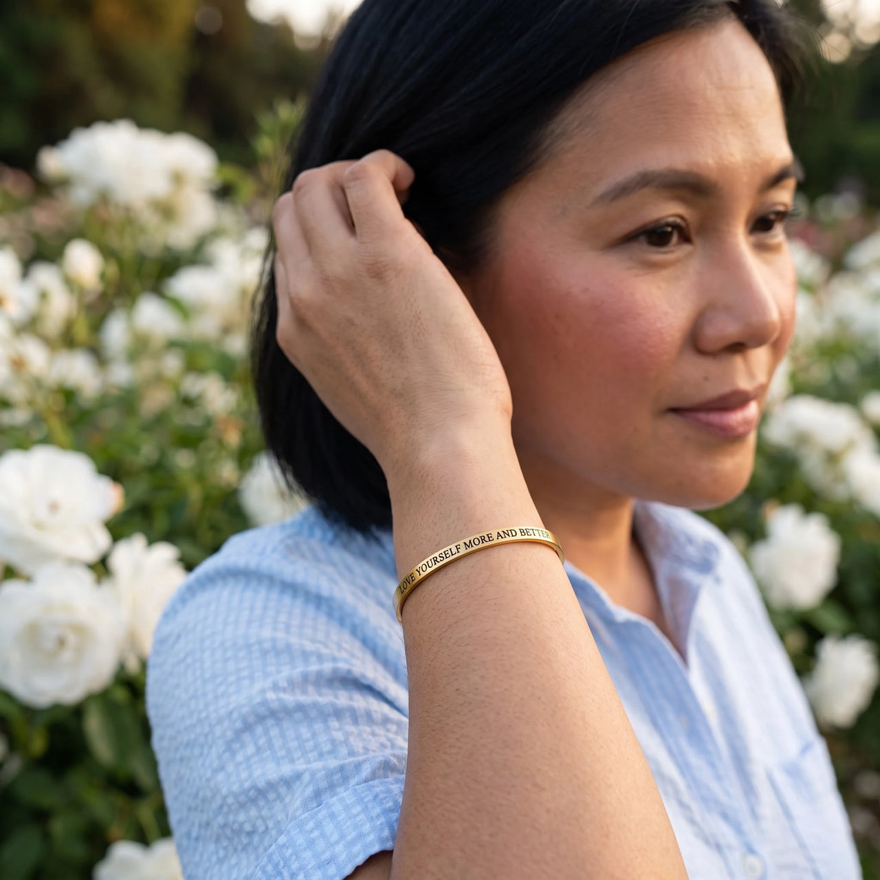 Woman gently touching her Love Yourself More And Better bracelet in gold | SKU: lymab-g