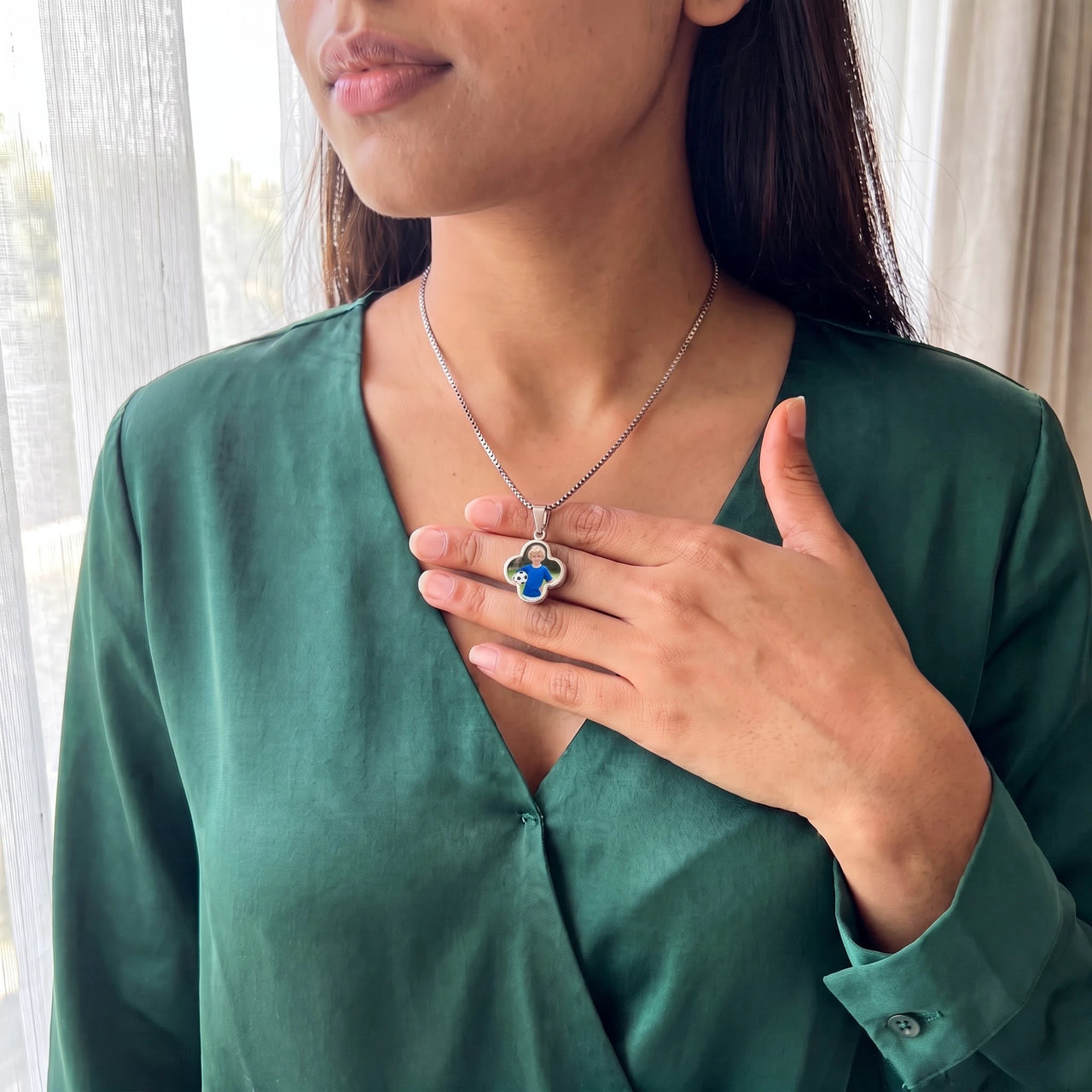 Woman in an emerald blouse warming the silver clover pendant with her thumb to reveal the photo | SKU: TPH-CLVN-SILVER