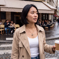 Thumbnail for Woman in a trench coat with a coffee by a Paris café, wearing the gold secret drop photo necklace | SKU: TPH-DRPN-GOLD
