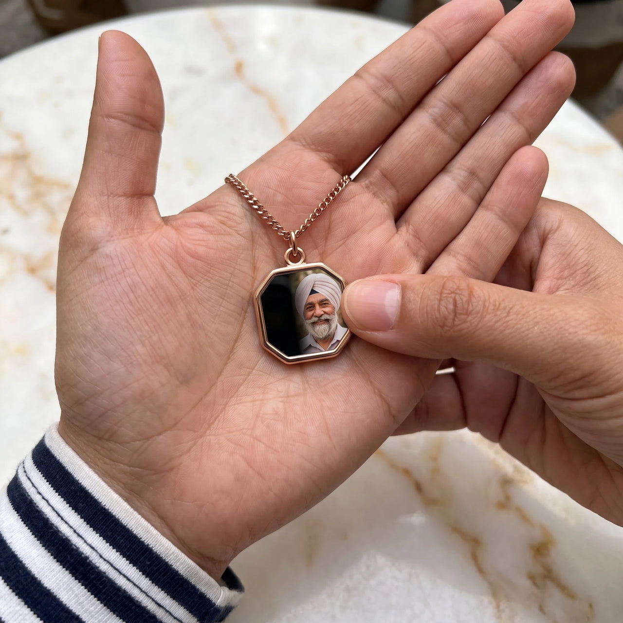 Thumb warming the rose gold octagon pendant: the hidden photo appears under the thumb while the rest stays black | SKU: TPH-OCTN-ROSEGOLD