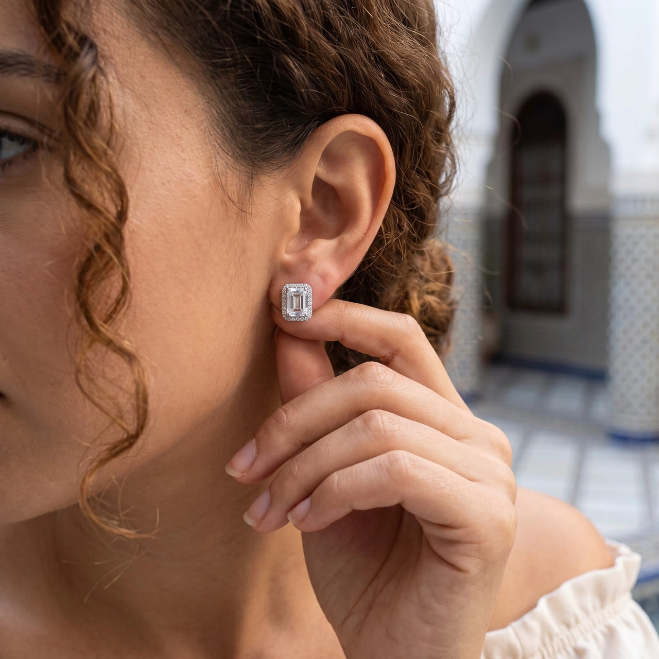 Woman gently touching her silver stud earrings | SKU: 22683128